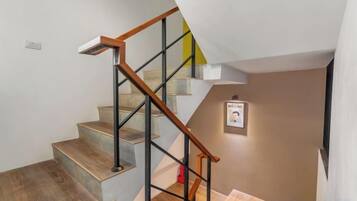 A staircase with wooden handrails and metal balusters, leading to a landing with a framed picture.