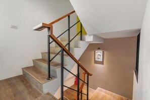 A staircase with wooden handrails and metal balusters, leading to a landing with a framed picture. - Xinhaiminsu (Hualien)