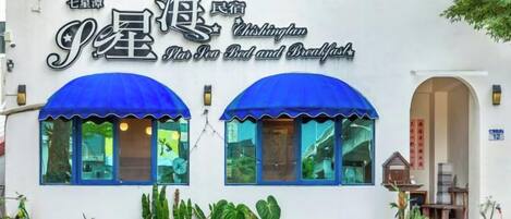 Un edificio con un letrero que dice 'P.S. Bed and Breakfast' y cuenta con dos toldos azules sobre las ventanas.