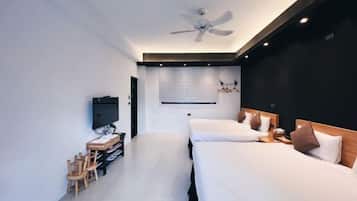 Une chambre d’hôtel moderne équipée de deux lits, d’une télévision, d’un bureau avec des chaises et d’un ventilateur de plafond.