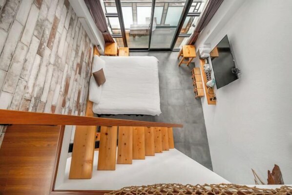 A modern interior with a wooden staircase, a bed, a flat-screen TV, and a view through a glass door. - Xinhaiminsu (Hualien)