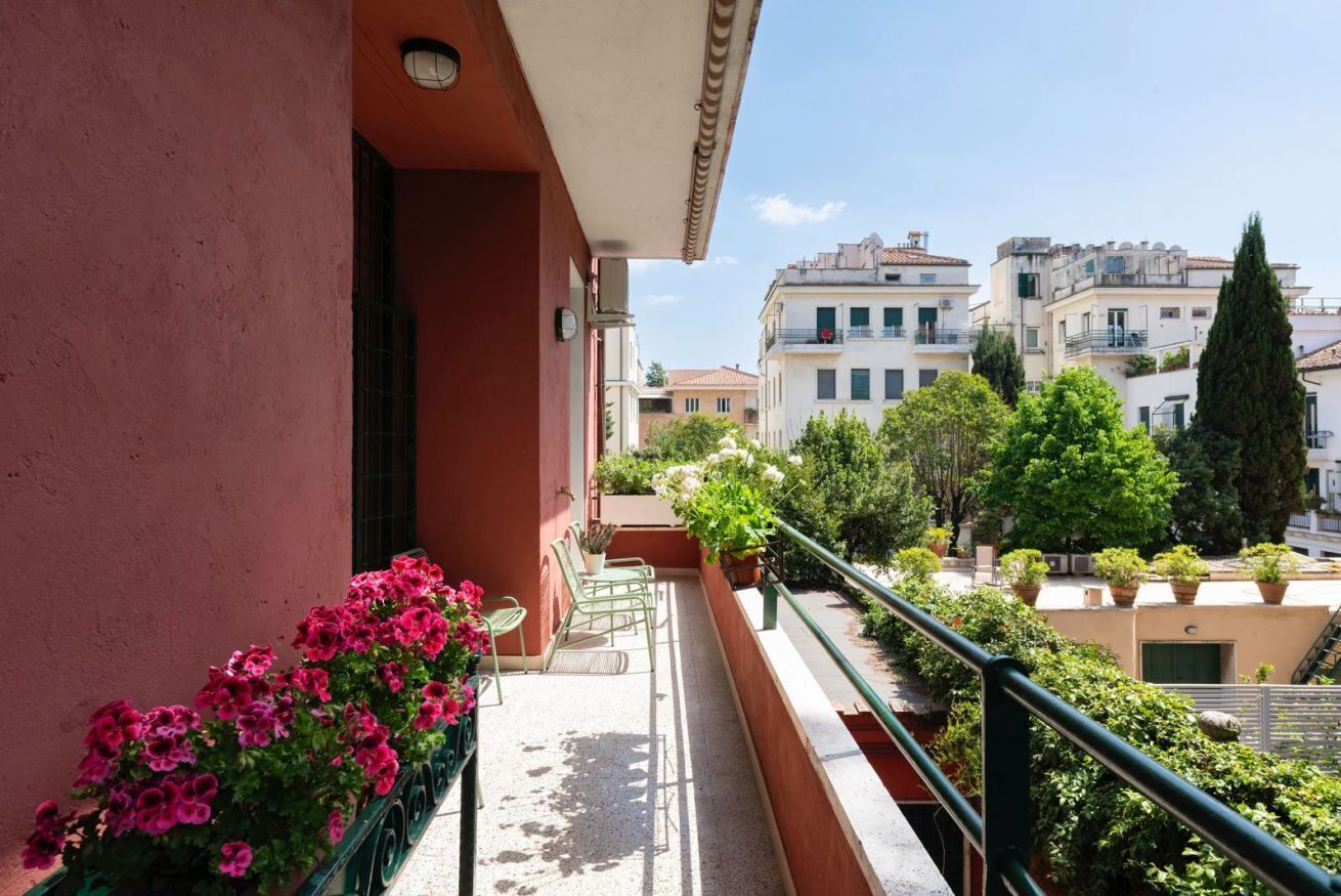 A balcony with potted plants and a view of surrounding buildings.