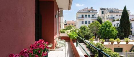 A balcony with potted plants and a view of surrounding buildings.