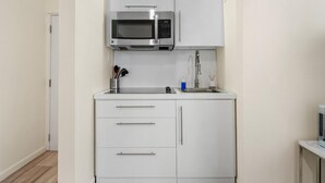A compact kitchenette with a built-in microwave, a sink, and white cabinetry. - Central Condado Trendy Escape (San Juan)