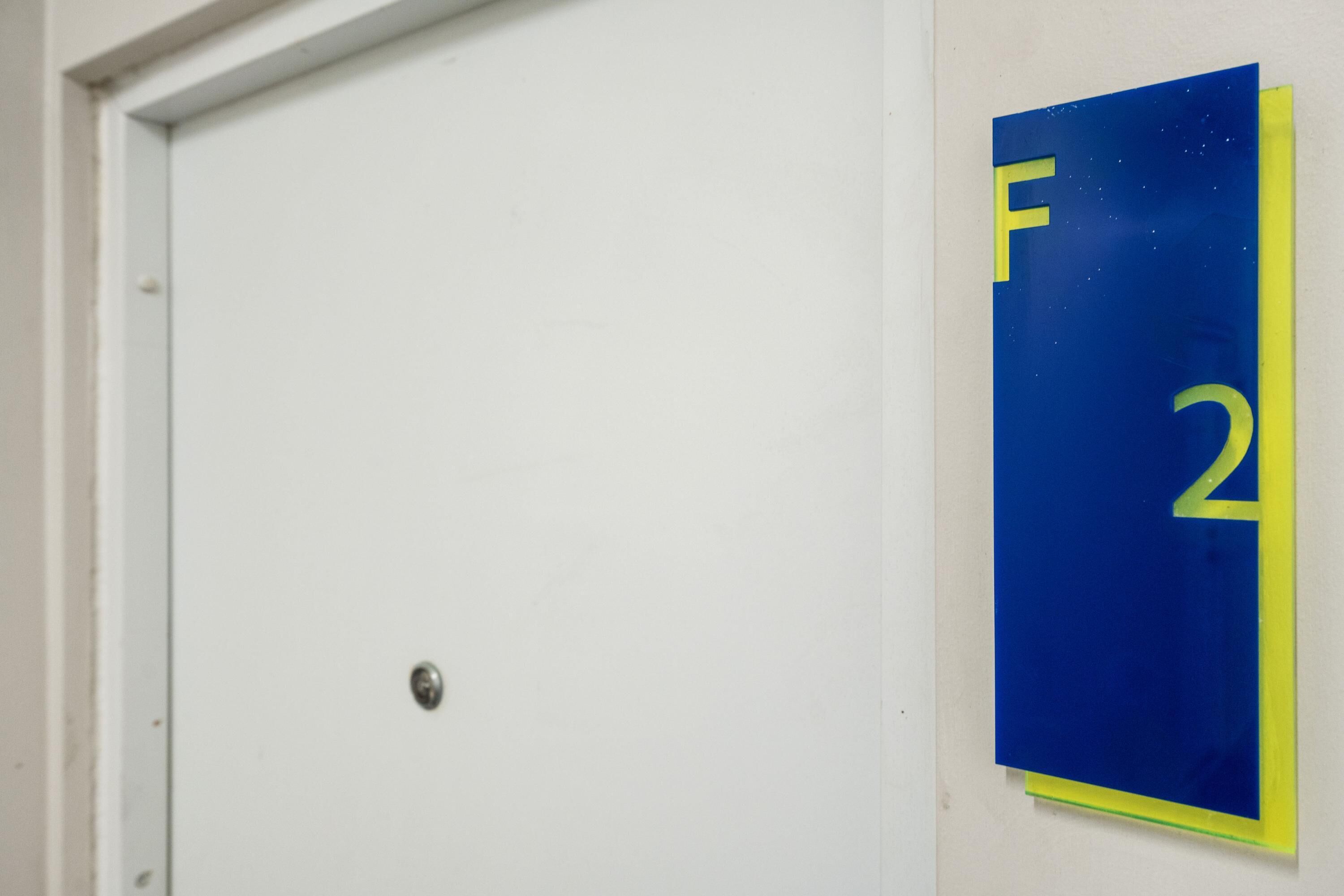 Une porte avec une plaque bleue indiquant le numéro de la pièce : 2.