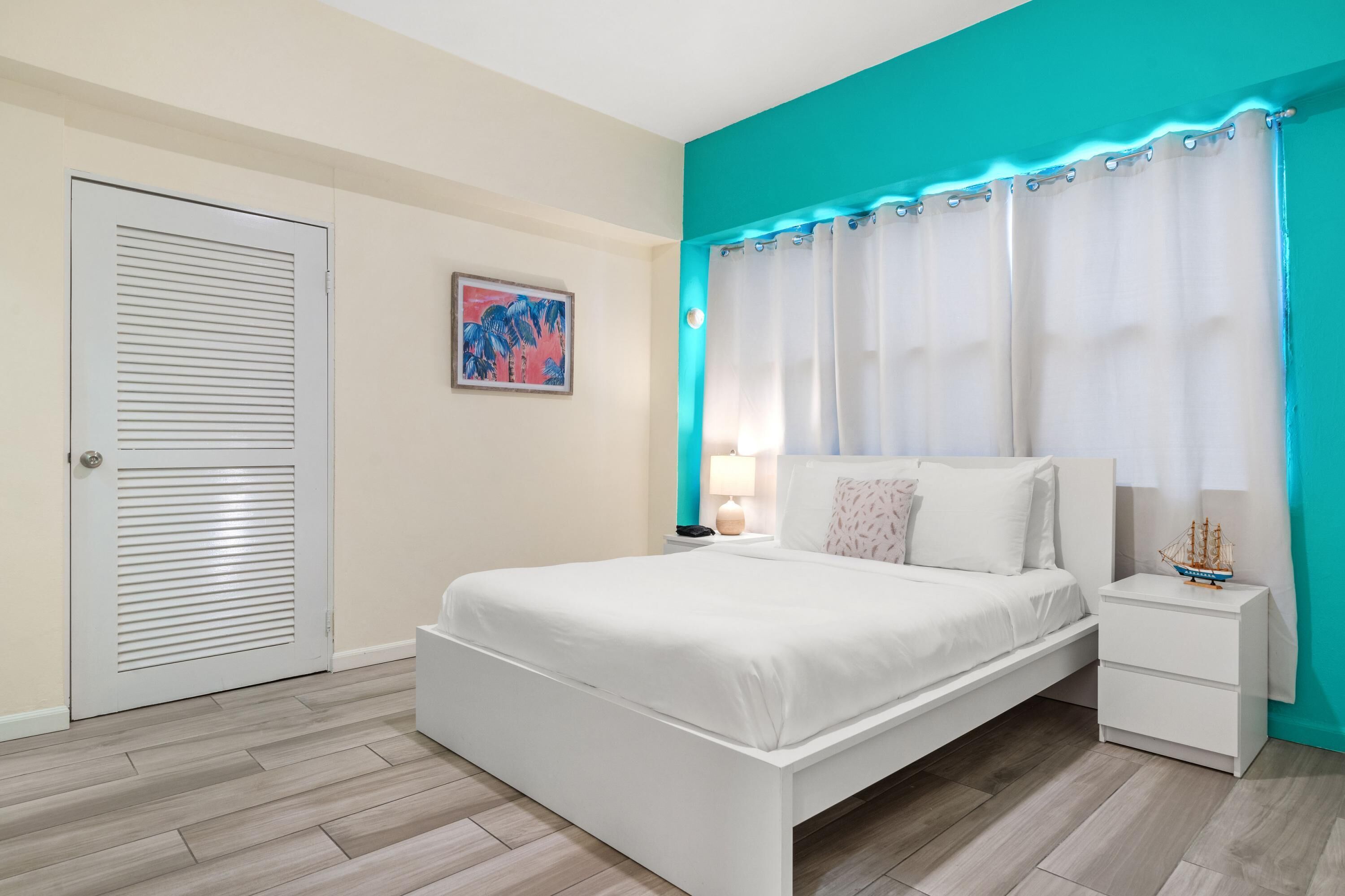 A bedroom with a bed, nightstand, and a door.