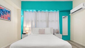 A bedroom with a bed, a nightstand, a lamp, a mirror, and an air conditioning unit. - Central Condado Trendy Escape (San Juan)