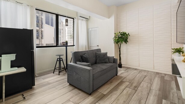 A modern living room with a grey sofa, a small table, and a potted plant. - Central Condado Trendy Escape (San Juan)