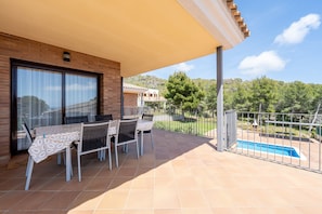 A covered patio with a table and chairs, a swimming pool, and a view of a hilly landscape. - Holiday Home 'Casa Tico' with Private Pool, Wi-Fi (Roda De Bara)