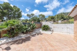 A patio area with a tiled floor, surrounded by plants and a brick wall. - Holiday Home 'Casa Tico' with Private Pool, Wi-Fi (Roda De Bara)