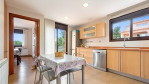 A modern kitchen with wooden cabinets, a dishwasher, and a dining area with a table and chairs. - Holiday Home 'Casa Tico' with Private Pool, Wi-Fi (Roda De Bara)