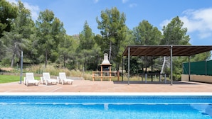 A swimming pool with lounge chairs, a covered seating area, and a natural backdrop of trees. - Holiday Home 'Casa Tico' with Private Pool, Wi-Fi (Roda De Bara)