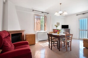 A living room with a fireplace, a dining table with chairs, a television, and a sofa.