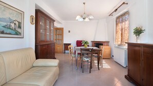 A living room with a sofa, dining table, chairs, a cabinet, and a painting on the wall. - Apartment 'Da Dri´' with Private Terrace, Private Garden and Balcony (Brugnato)