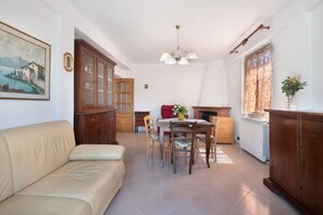 Un salon comprenant un canapé, une table à manger, des chaises, un meuble et un tableau accroché au mur.