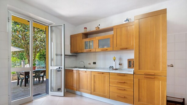 A kitchen with wooden cabinets, a countertop, and a sliding glass door leading to an outdoor area. - Apartment 'Da Dri´' with Private Terrace, Private Garden and Balcony (Brugnato)