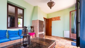 A room with a sofa, a table with a lantern, a brick wall, a door, and a radiator. - Holiday Home 'Esencia Del Paladin' with Mountain Views (Zufre)
