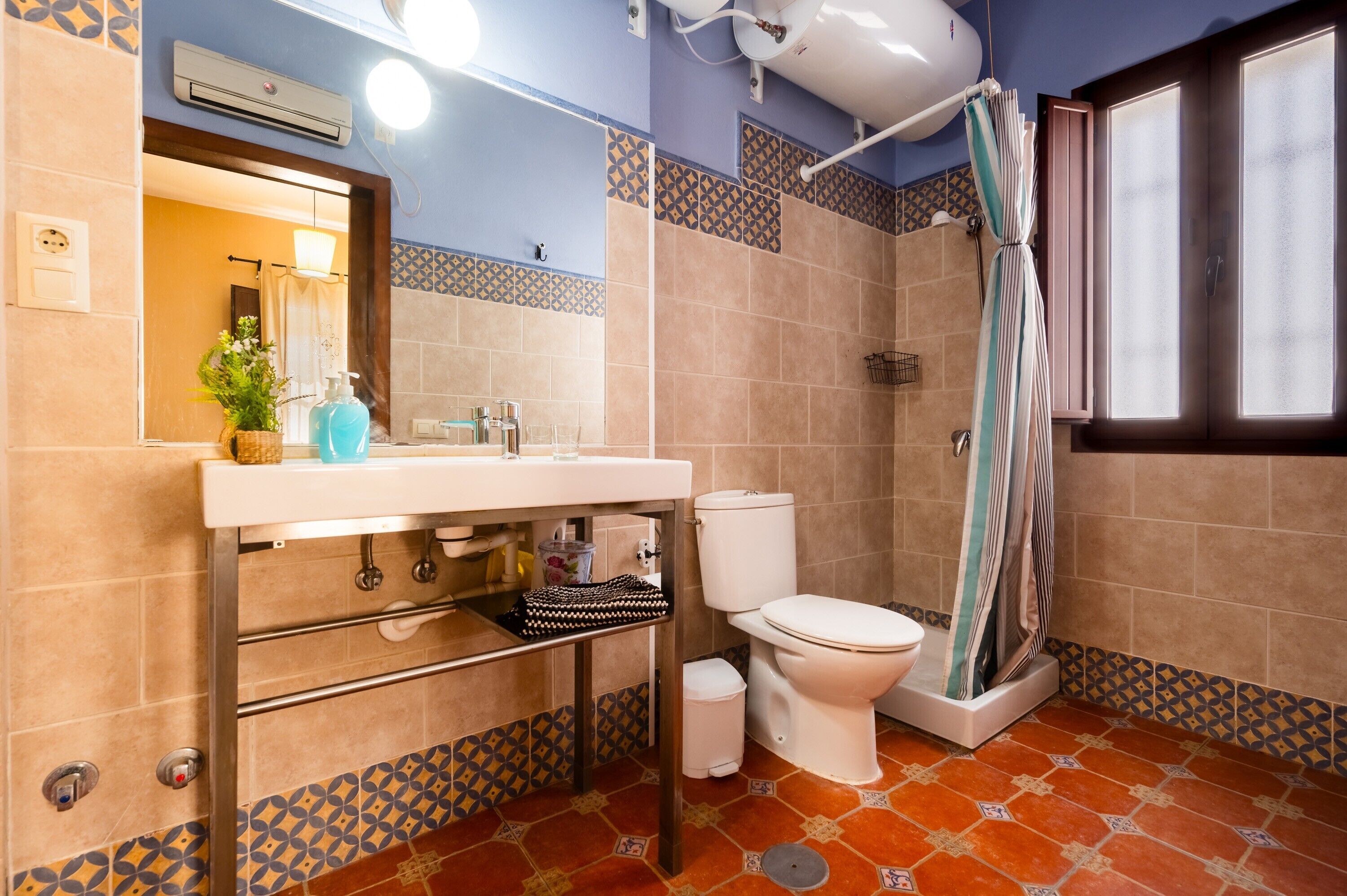 A bathroom with a sink, toilet, shower curtain, and patterned tiles.