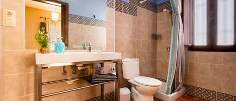 A bathroom with a sink, toilet, shower curtain, and patterned tiles.