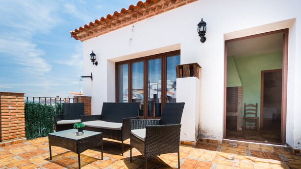 A patio with wicker furniture, a tiled floor, and a white building with a tiled roof. - Holiday Home 'Esencia Del Paladin' with Mountain Views (Zufre)