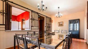 A dining area with a glass table and chairs, a chandelier, and a black cabinet. - Holiday Home 'Esencia Del Paladin' with Mountain Views (Zufre)