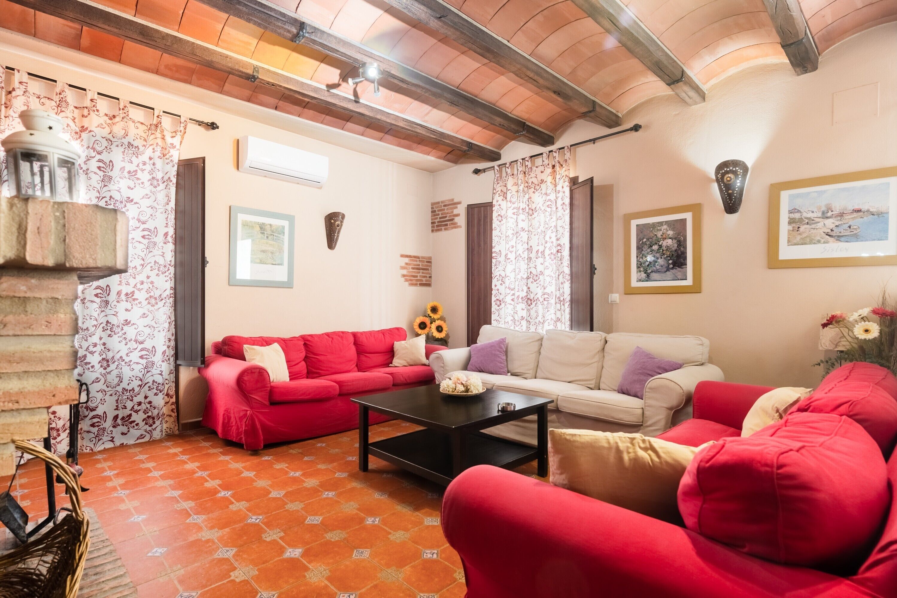 Ein Wohnzimmer mit einem roten Sofa, einem weißen Sofa, einem schwarzen Couchtisch und einem gemusterten Boden.