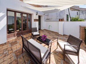 An outdoor patio with wicker furniture, a tiled floor, and a glass door leading to an interior space.
