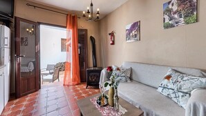 A living room with a sofa, a table with decorative items, a fireplace, and a painting on the wall.