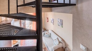 A multi-level interior with a spiral staircase, a sofa, and a bed.