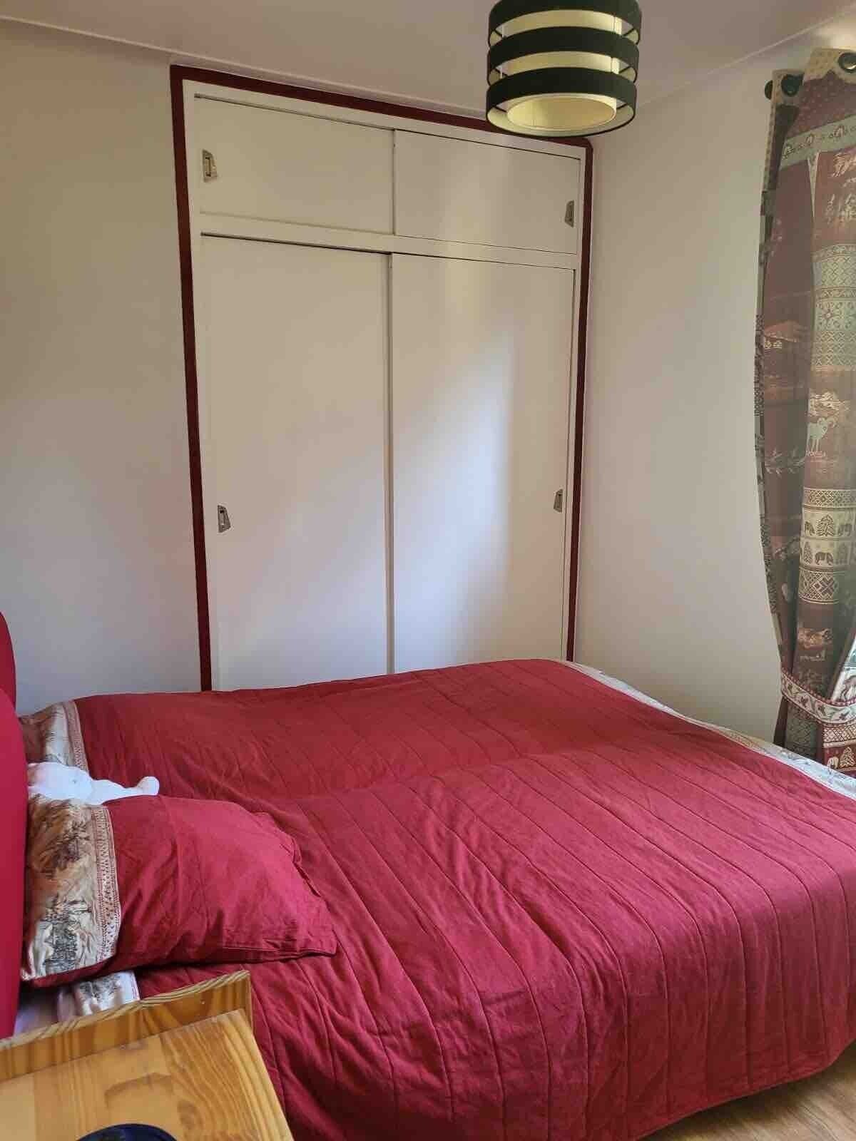 Une chambre à coucher avec un lit, une armoire et un luminaire suspendu.