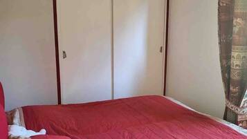 Une chambre à coucher avec un lit, une armoire et un luminaire suspendu.