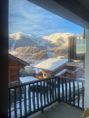 A balcony with a view of snow-covered mountains and wooden cabins.