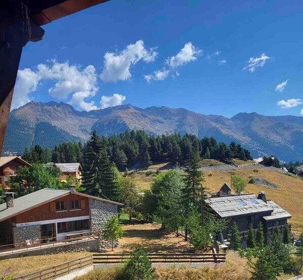 A mountain view with houses, a wooden fence, and a clear sky.