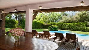 An outdoor patio with a wooden table and chairs, a pool, and a view of a garden and mountains. - Country Home 'Gran Castanyer' with Mountain View, Private Pool and Wi-Fi (Viladrau)