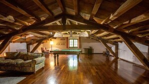 An attic room with wooden beams, a billiards table, a sofa, and a lamp. - Country Home 'Gran Castanyer' with Mountain View, Private Pool and Wi-Fi (Viladrau)