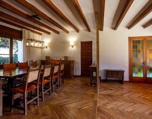 A dining area with wooden furniture, a herringbone floor, and exposed wooden beams.