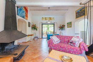 Een woonkamer met een open haard, een bank, een eettafel en uitzicht op het landschap.