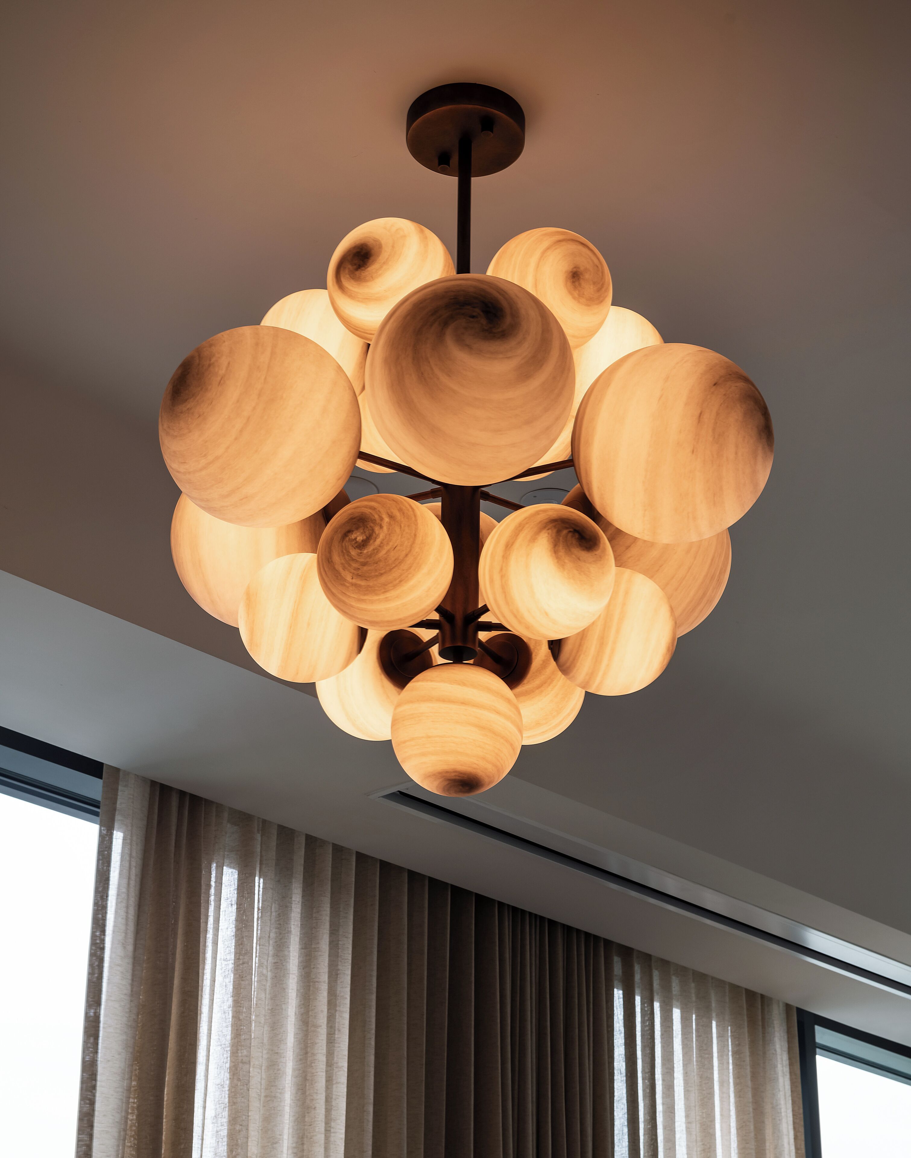 Un candelabro moderno con múltiples pantallas de madera colgando de una estructura central negra.