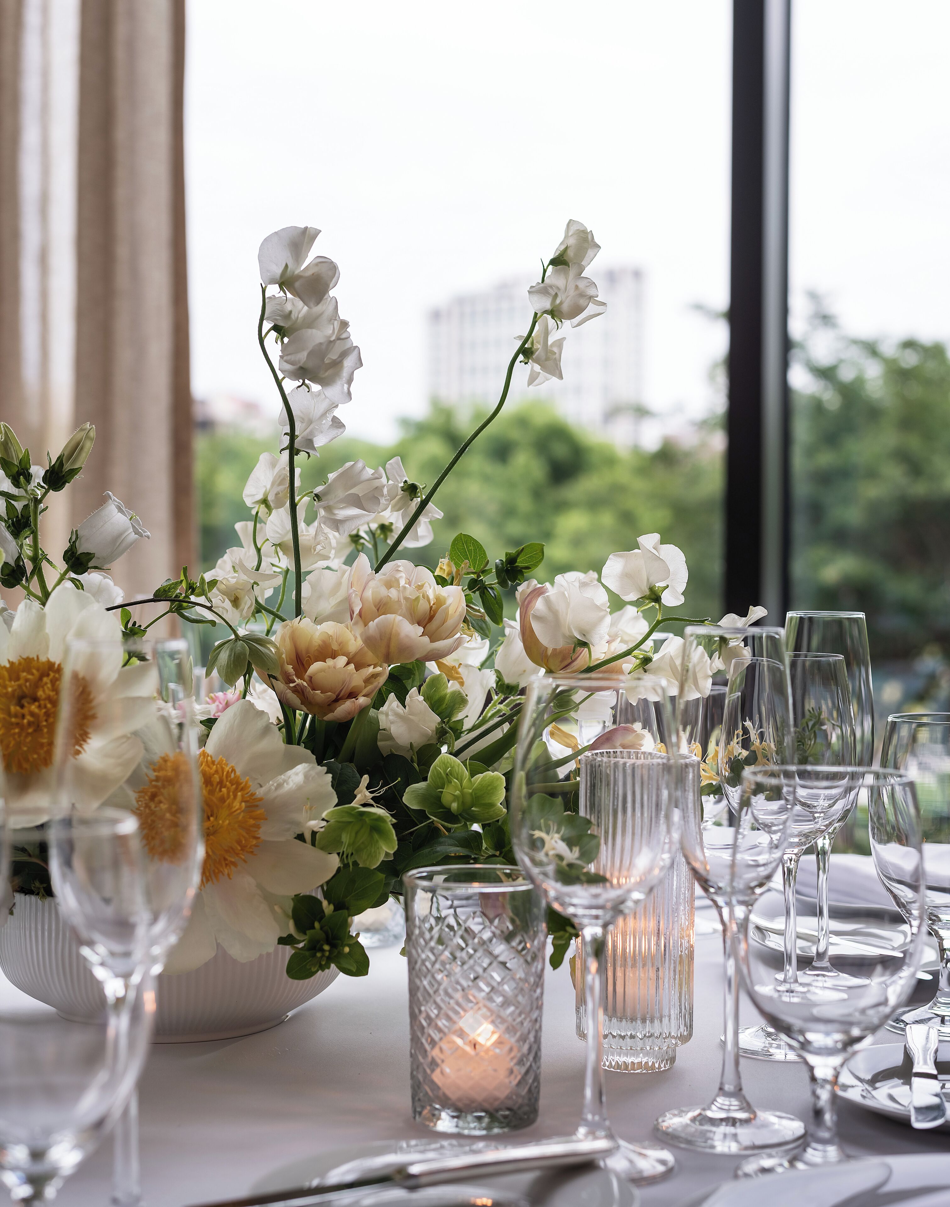 A table set with white flowers, clear glassware, and a candle.