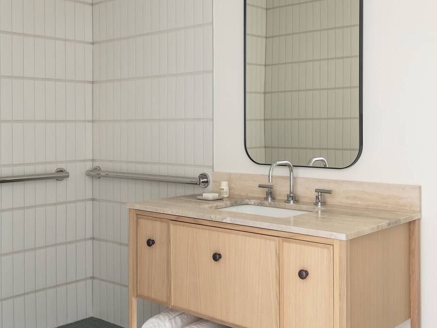 A modern bathroom with a shower, a sink with a mirror, and a towel rack.