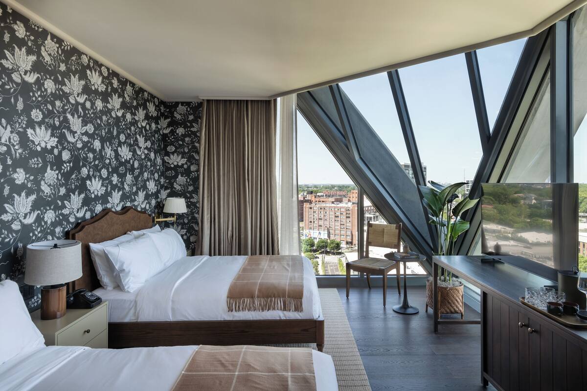 A hotel room with a large bed, a desk, a chair, and a view of the city.