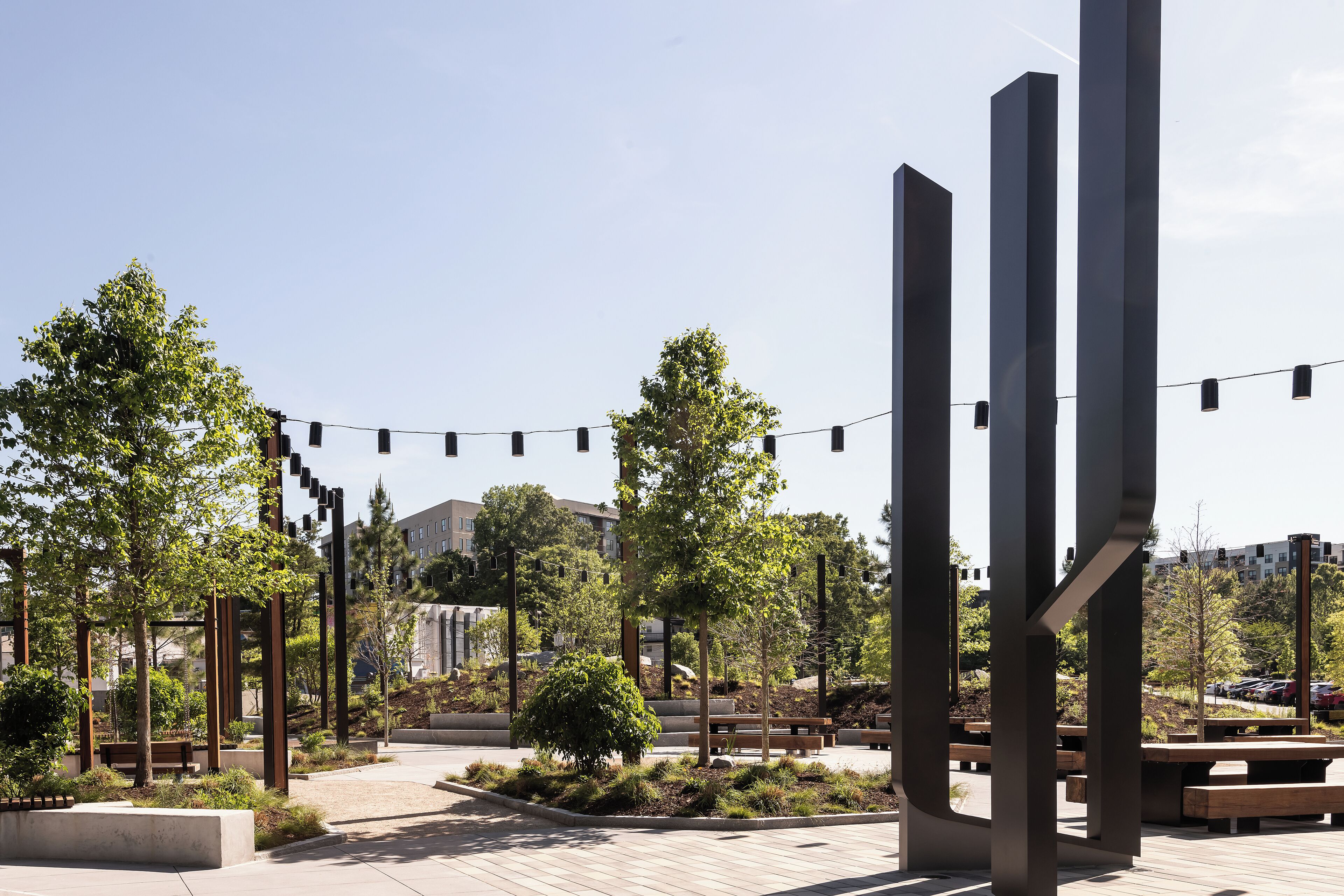 An outdoor plaza with benches, trees, and modern metal structures.