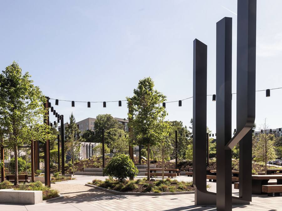 An outdoor plaza with benches, trees, and modern metal structures.