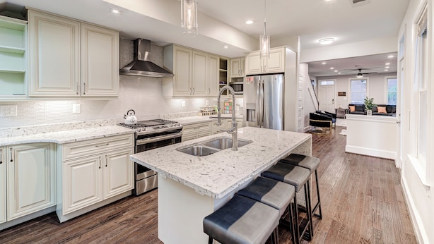A modern kitchen with white cabinetry, a large island with bar stools, stainless steel appliances, and pendant lighting. - Contemporary, Cozy, & Convenient in Old Town Alexandria (Alexandria)