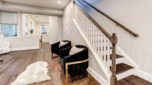 A modern interior with a wooden staircase, a fluffy rug, and two black chairs with cushions. - Contemporary, Cozy, & Convenient in Old Town Alexandria (Alexandria)