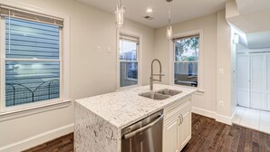 A kitchen with a marble countertop, stainless steel sink, and wooden flooring. - Contemporary, Cozy, & Convenient in Old Town Alexandria (Alexandria)