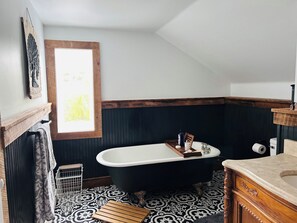 Un baño con una bañera independiente, un tocador de madera y un piso con diseño.