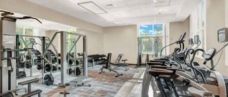 A gym with various exercise equipment, including treadmills, weight machines, and free weights.