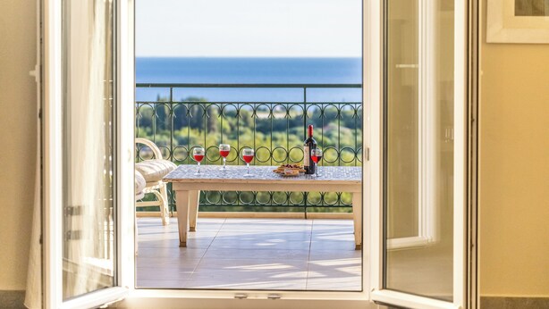 Un balcon avec une table dressée pour deux personnes, une bouteille de vin et des verres.