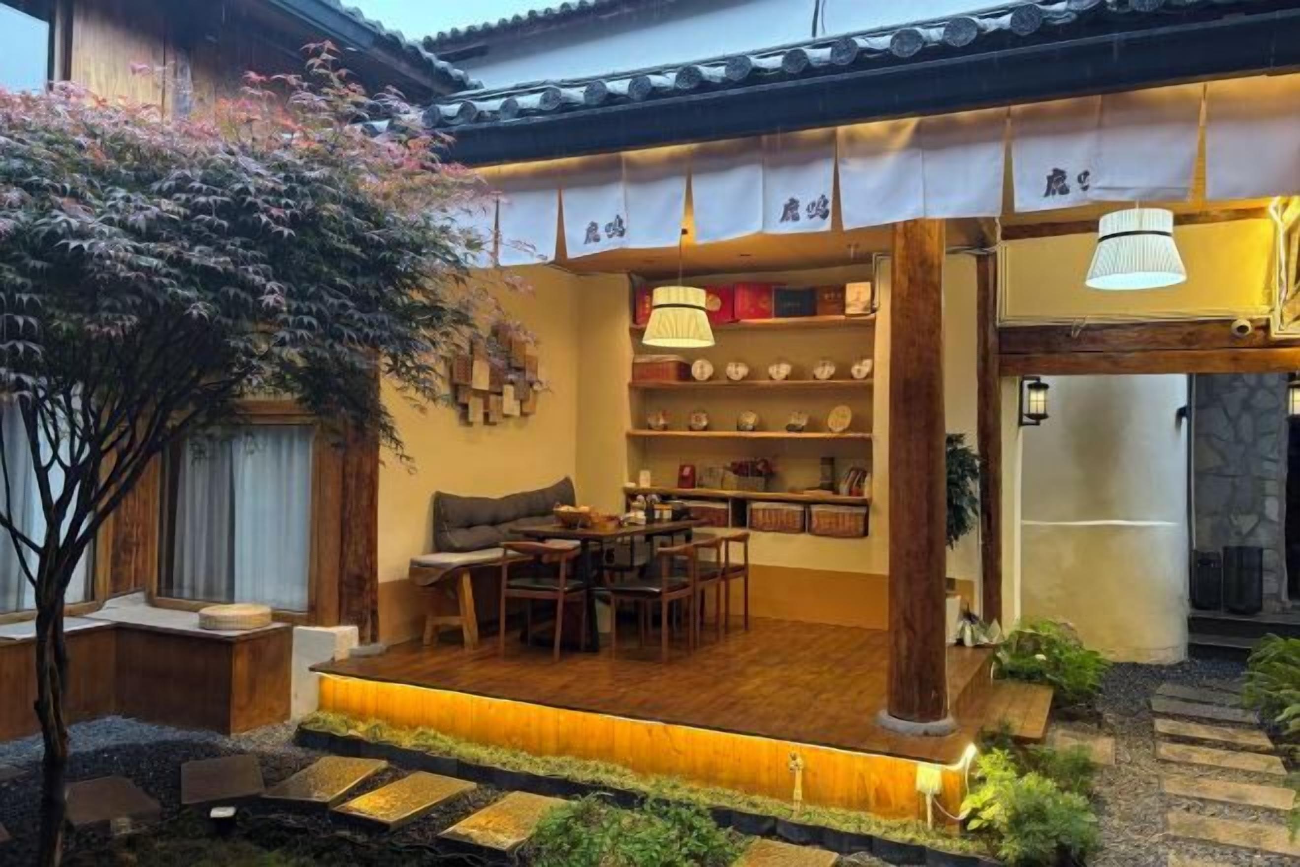 Un interior tradicional japonés con suelo de madera, asientos de tatami y un estante empotrado con adornos.